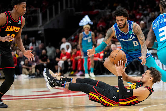 Apr 13, 2022; Atlanta, Georgia, USA; Atlanta Hawks guard Trae Young (11) passes the ball from the floor to forward De'Andre Hunter (12) behind Charlotte Hornets forward Miles Bridges (0) during the second half at State Farm Arena.